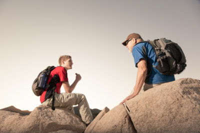 Two Hikers with Backpacks Relax for a Snack Break